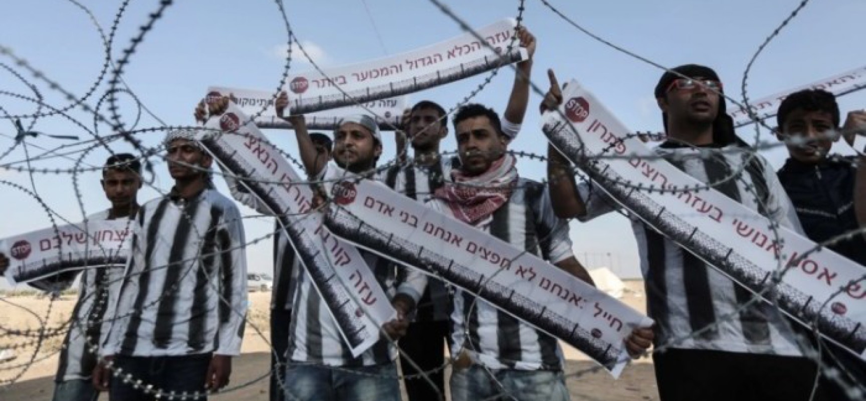 De jeunes Palestiniens manifestent à la frontière de Gaza en arborant des banderoles qui disent en hébreu : « Soldat, nous ne sommes pas des objets, nous sommes des êtres humains »