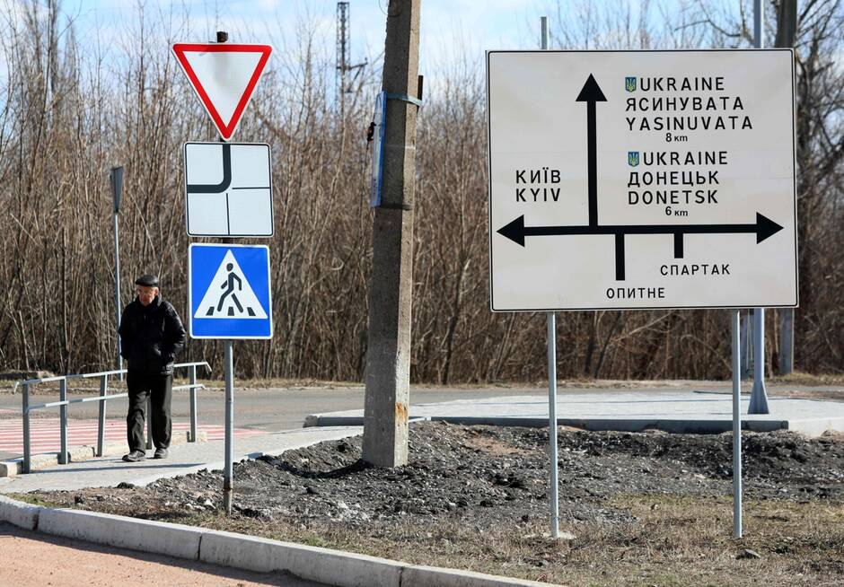 Un homme passe devant un panneau routier dans la ville d’Avdiivka, dans la région de Donetsk, le 21 février 2022. Photo d’illustration | ALEKSEY FILIPPOV/AFP