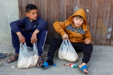 Des enfants palestiniens portant des sachets de pains à Gaza (Illustration)