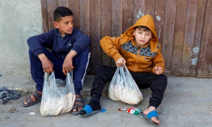 Des enfants palestiniens portant des sachets de pains à Gaza (Illustration)