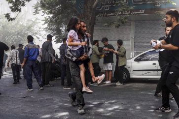 Un homme porte un enfant blessé après une agression israélienne contre le centre-ville de Téhéran.