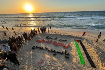 Une peinture sur sable sur la plage de Gaza sur laquelle est inscrite: Depuis Gaza, nous abandonnerons pas la Palestine Ô Sayed Hassan.